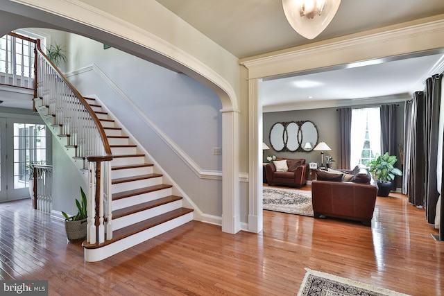 stairway with arched walkways and hardwood / wood-style flooring