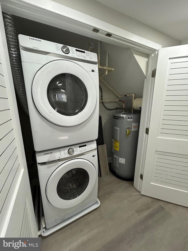 washroom with laundry area, stacked washer and dryer, wood finished floors, and electric water heater