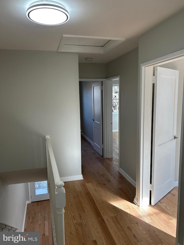 hall with baseboards, an upstairs landing, and wood finished floors