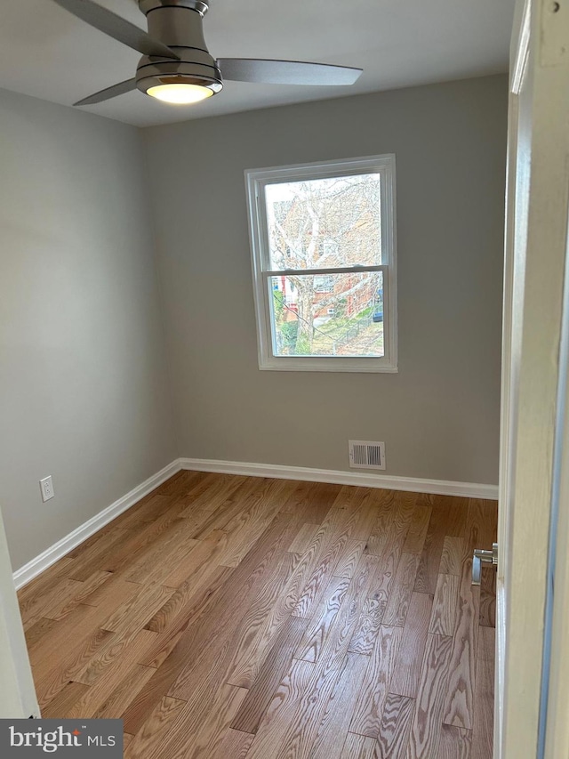 spare room with visible vents, baseboards, wood finished floors, and a ceiling fan