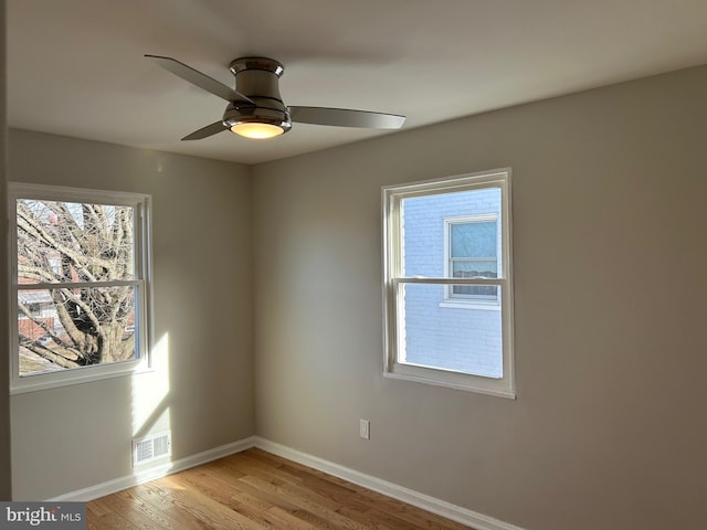 spare room with light wood finished floors, visible vents, a healthy amount of sunlight, and baseboards