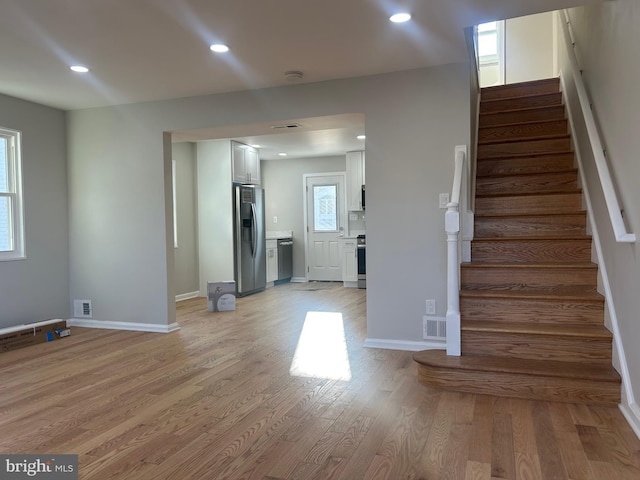 unfurnished living room featuring visible vents, baseboards, recessed lighting, stairs, and light wood-style floors