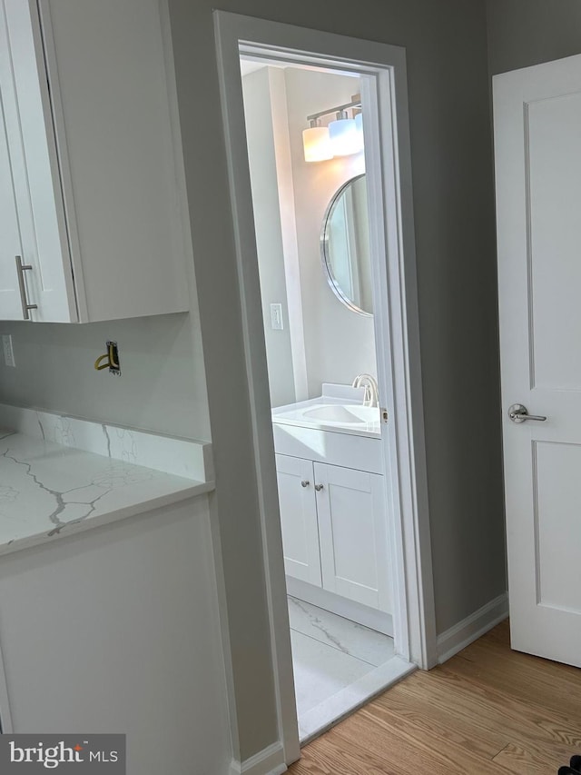 bathroom featuring vanity, wood finished floors, and baseboards