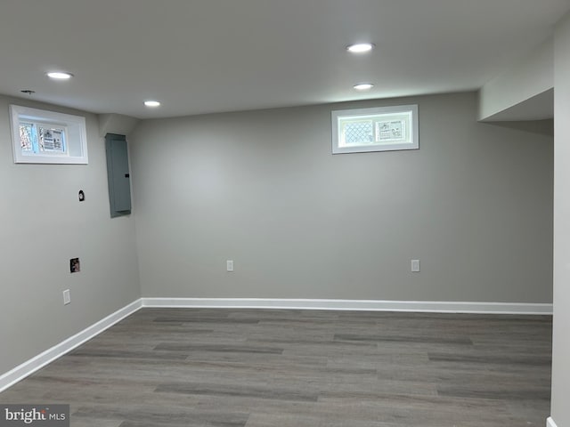 basement featuring recessed lighting, electric panel, wood finished floors, and baseboards