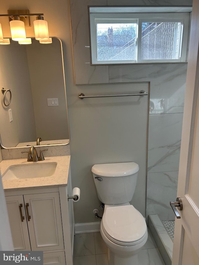 bathroom with toilet, marble finish floor, a stall shower, baseboards, and vanity