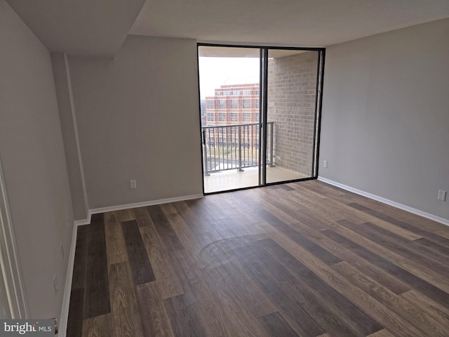 empty room with dark wood finished floors, baseboards, and expansive windows