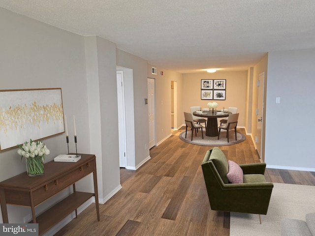 interior space featuring visible vents, a textured ceiling, baseboards, and wood finished floors