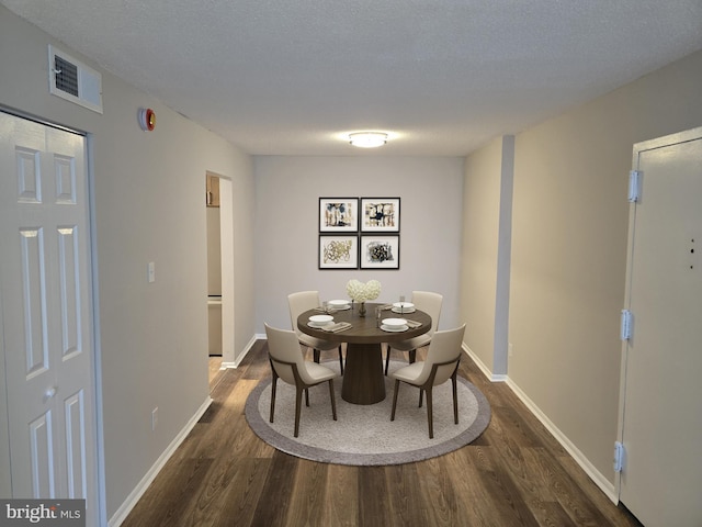 dining space with visible vents, a textured ceiling, dark wood-type flooring, and baseboards