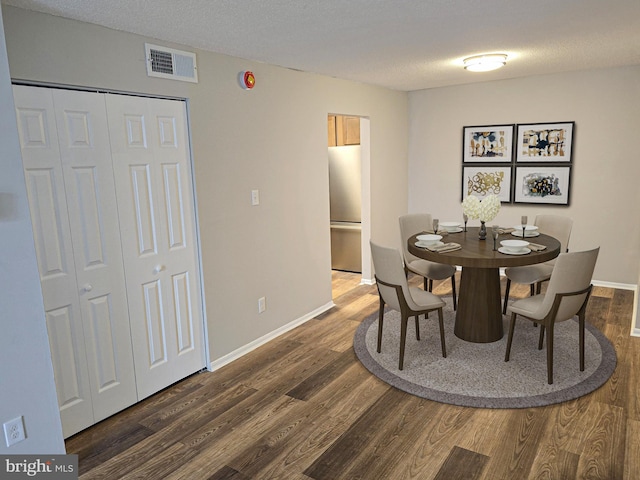 dining room with visible vents, a textured ceiling, baseboards, and wood finished floors