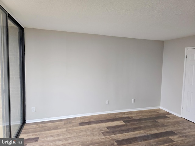 spare room featuring wood finished floors, baseboards, and a textured ceiling