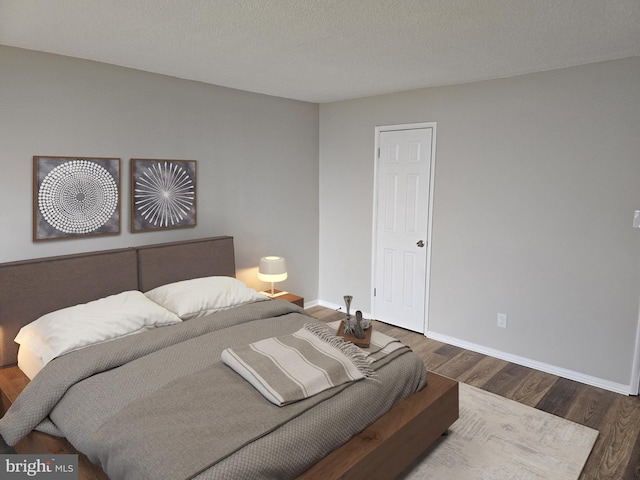 bedroom with wood finished floors, baseboards, and a textured ceiling