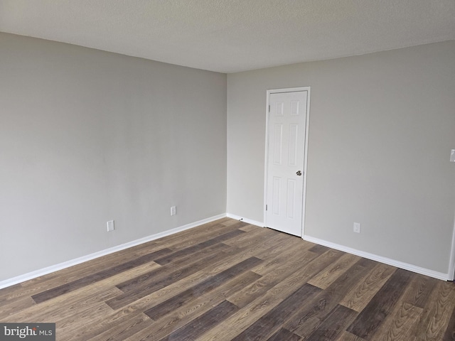 unfurnished room featuring dark wood-style floors, baseboards, and a textured ceiling