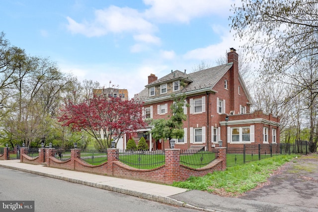 view of front facade featuring a front lawn, brick siding, a fenced front yard, and a chimney