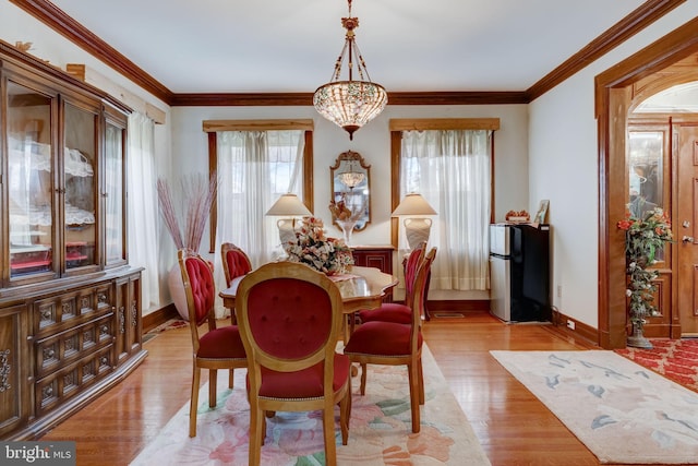 dining area featuring an inviting chandelier, crown molding, light wood-style flooring, and baseboards