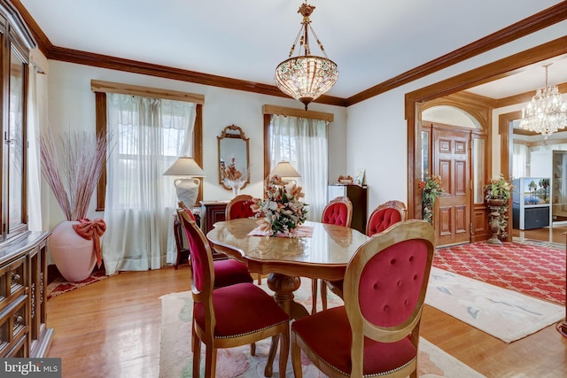 dining area featuring a notable chandelier, light wood-style flooring, and crown molding