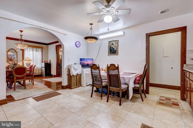 dining area with baseboards, light tile patterned flooring, arched walkways, ornamental molding, and a notable chandelier