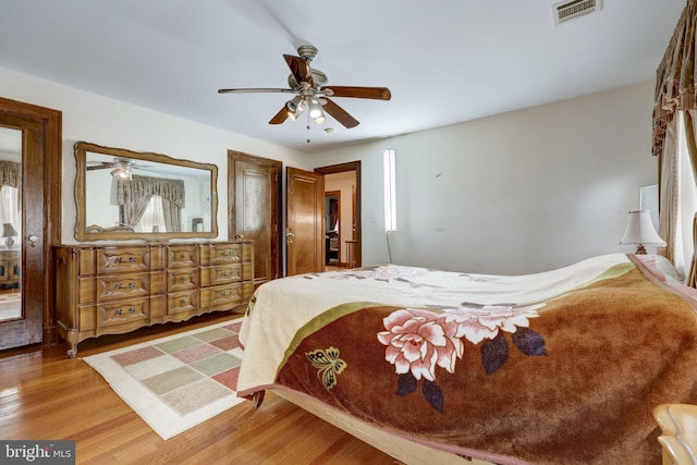 bedroom featuring ceiling fan, visible vents, and wood finished floors