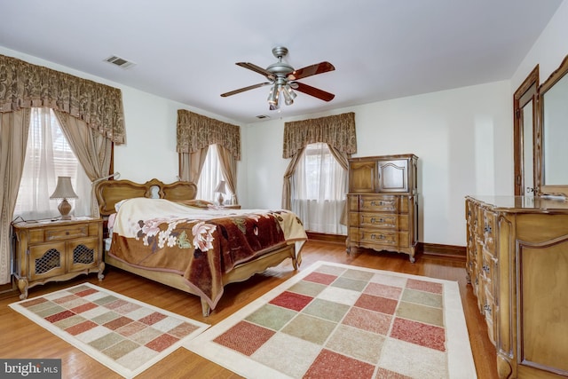 bedroom with visible vents, baseboards, a ceiling fan, and wood finished floors