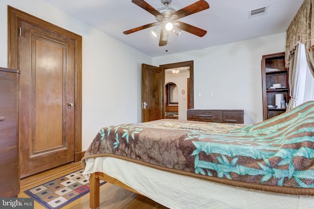 bedroom with light wood finished floors, visible vents, and a ceiling fan