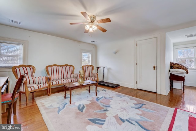 living area with wood finished floors, visible vents, and baseboards