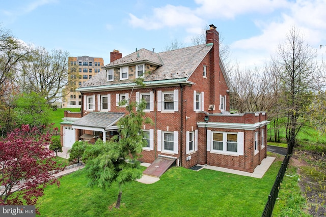 georgian-style home featuring brick siding, a high end roof, a chimney, and a front yard