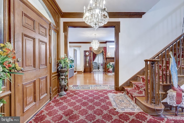 foyer entrance featuring stairway, baseboards, an inviting chandelier, and ornamental molding