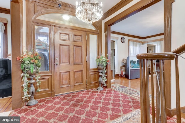 entrance foyer with wood finished floors, a notable chandelier, and ornamental molding