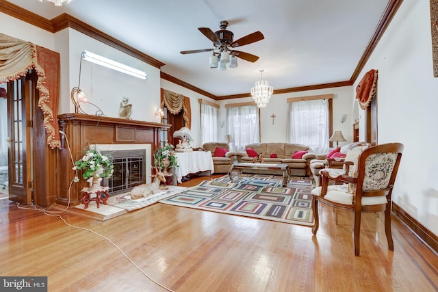 living room featuring a glass covered fireplace, wood finished floors, baseboards, and ornamental molding