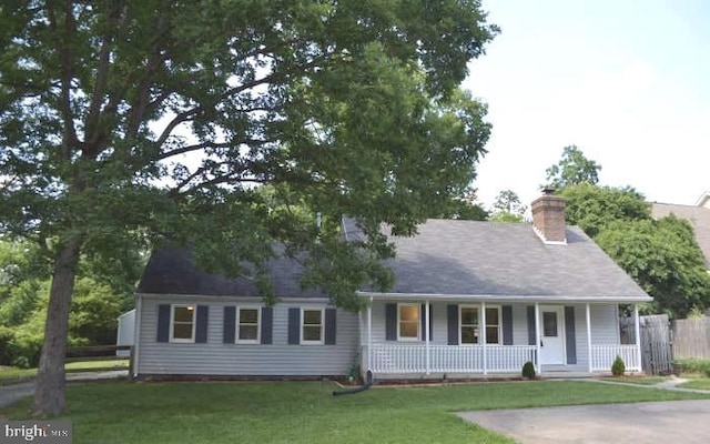 view of front of property with a porch, a chimney, and a front yard