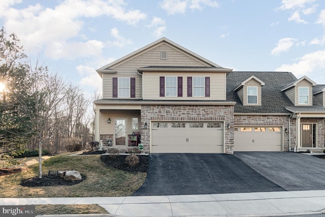 view of front of home with stone siding, driveway, a shingled roof, and a garage