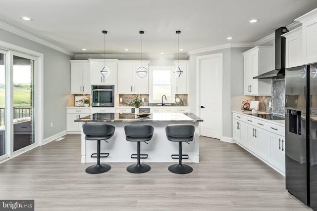 kitchen featuring a kitchen island, a kitchen breakfast bar, stainless steel appliances, and wall chimney exhaust hood