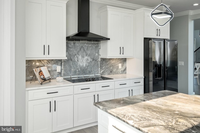 kitchen with white cabinetry, crown molding, wall chimney exhaust hood, black electric cooktop, and stainless steel fridge