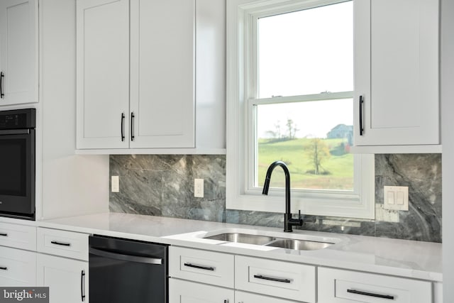 kitchen featuring white cabinetry, black appliances, tasteful backsplash, and a sink