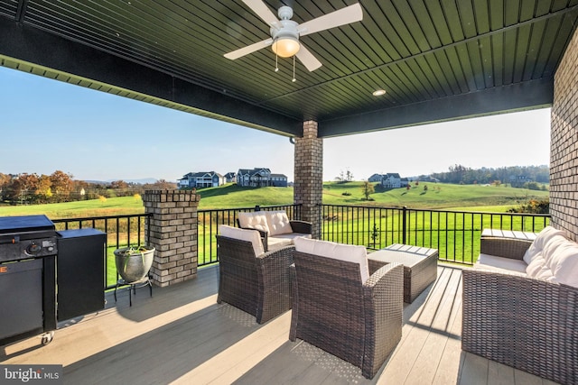 wooden deck with outdoor lounge area and a ceiling fan