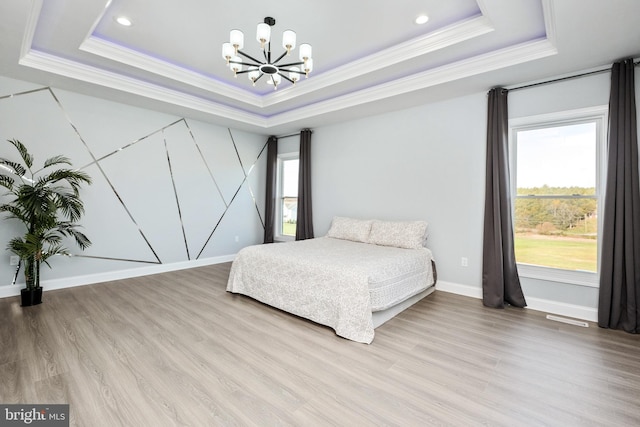 bedroom with baseboards, crown molding, light wood-style floors, a raised ceiling, and a chandelier