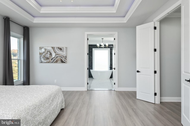 bedroom featuring a tray ceiling, wood finished floors, baseboards, and ornamental molding