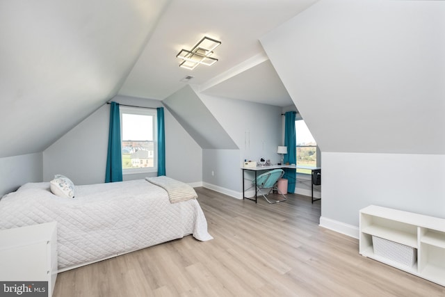 bedroom featuring lofted ceiling, baseboards, and wood finished floors