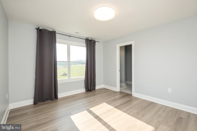 spare room with baseboards and light wood finished floors