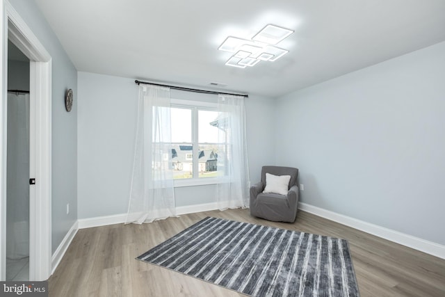 living area with visible vents, baseboards, and wood finished floors