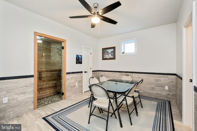 dining space with tile walls, light wood-style flooring, and a wainscoted wall