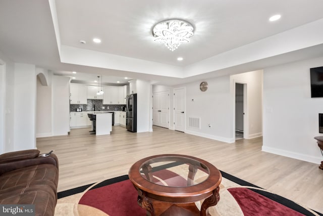 living area with visible vents, a notable chandelier, recessed lighting, light wood finished floors, and baseboards