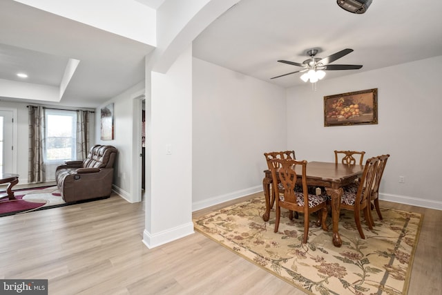 dining room featuring a ceiling fan, a raised ceiling, wood finished floors, and baseboards