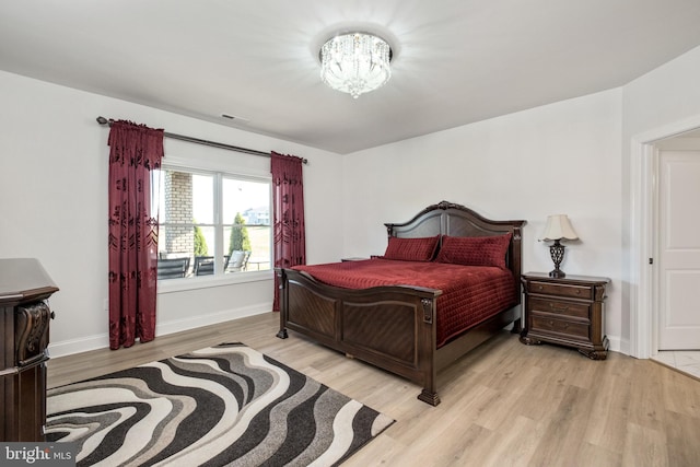 bedroom with visible vents, baseboards, light wood-style floors, and a notable chandelier