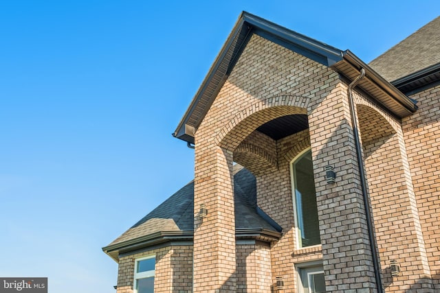 view of property exterior with brick siding and roof with shingles