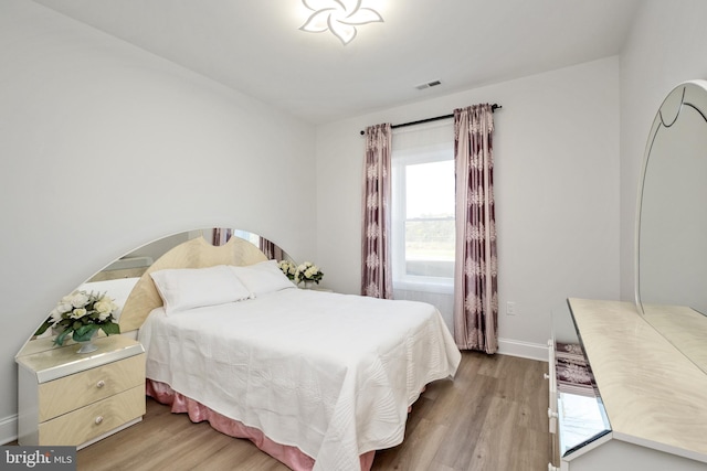 bedroom featuring visible vents, baseboards, and wood finished floors