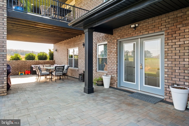 view of patio with outdoor dining space, a balcony, french doors, and fence