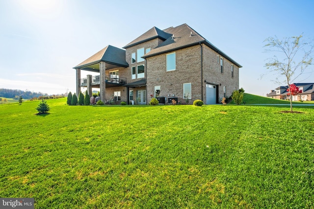 rear view of house featuring brick siding, central air condition unit, a yard, a garage, and a balcony