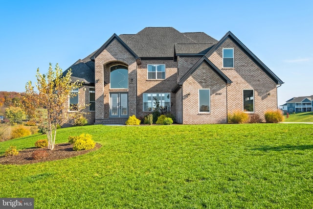 view of front of house featuring brick siding, french doors, and a front yard