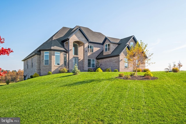 french provincial home with brick siding and a front yard