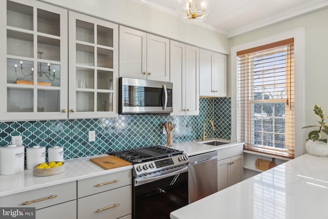 kitchen with a sink, tasteful backsplash, appliances with stainless steel finishes, crown molding, and glass insert cabinets